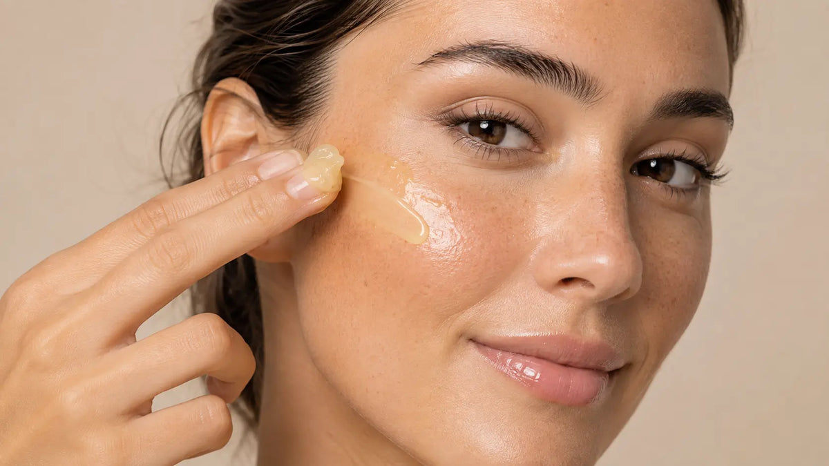 Mujer aplicando crema con vitamina C de color amarillo pálido sobre el rostro para mejorar la luminosidad, estimular el colágeno y ayudar a reducir manchas.